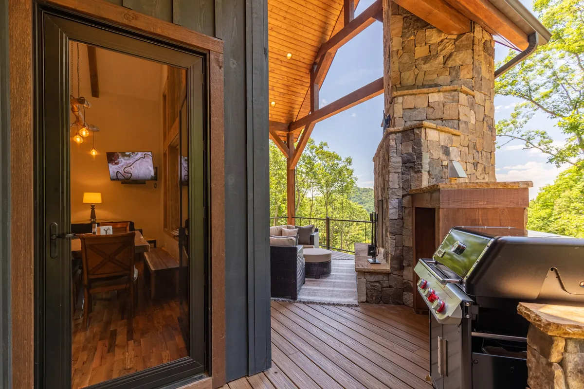 An outdoor seating area arranged around a stone chimney and grill creates an inviting space for barbecues, sunset viewing, and evening relaxation. Large glass doors connect the outdoors to the home's interior, blending indoor comfort with outdoor adventure.