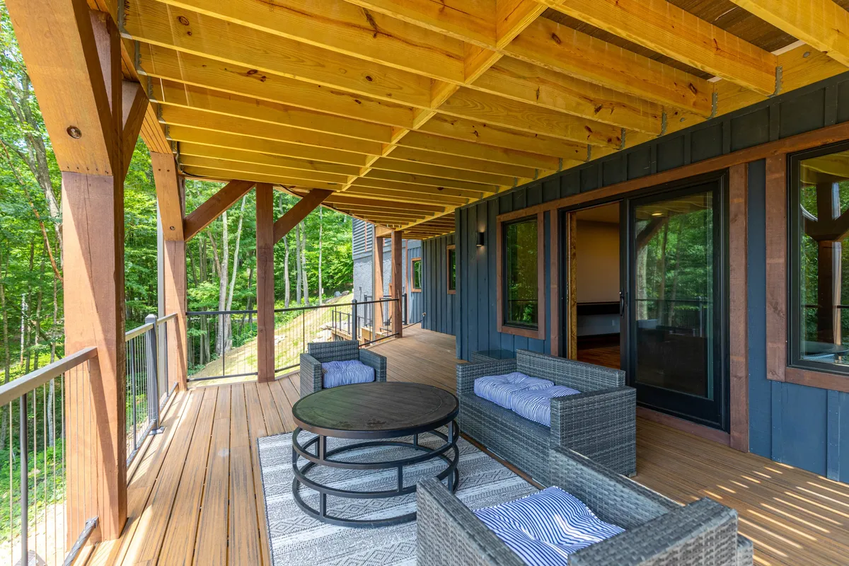 An inviting outdoor seating area featuring a round coffee table, wooden beams, and lush surrounding greenery. The ambiance is tranquil and perfect for enjoying nature, morning yoga, or evening gatherings by the fire pit.